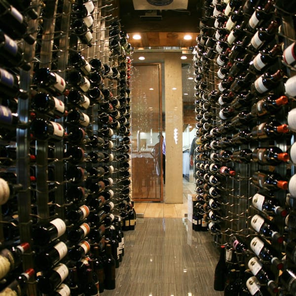 A wine cellar with rows of wine bottles stacked on tall metal racks.